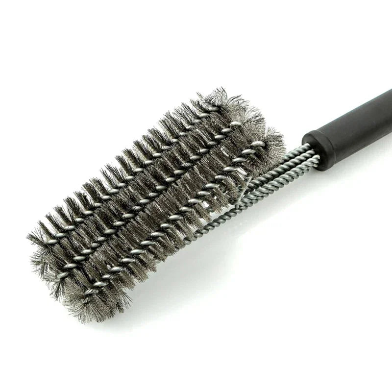 Close-up of a heavy-duty stainless steel BBQ grill cleaning brush with black handle
