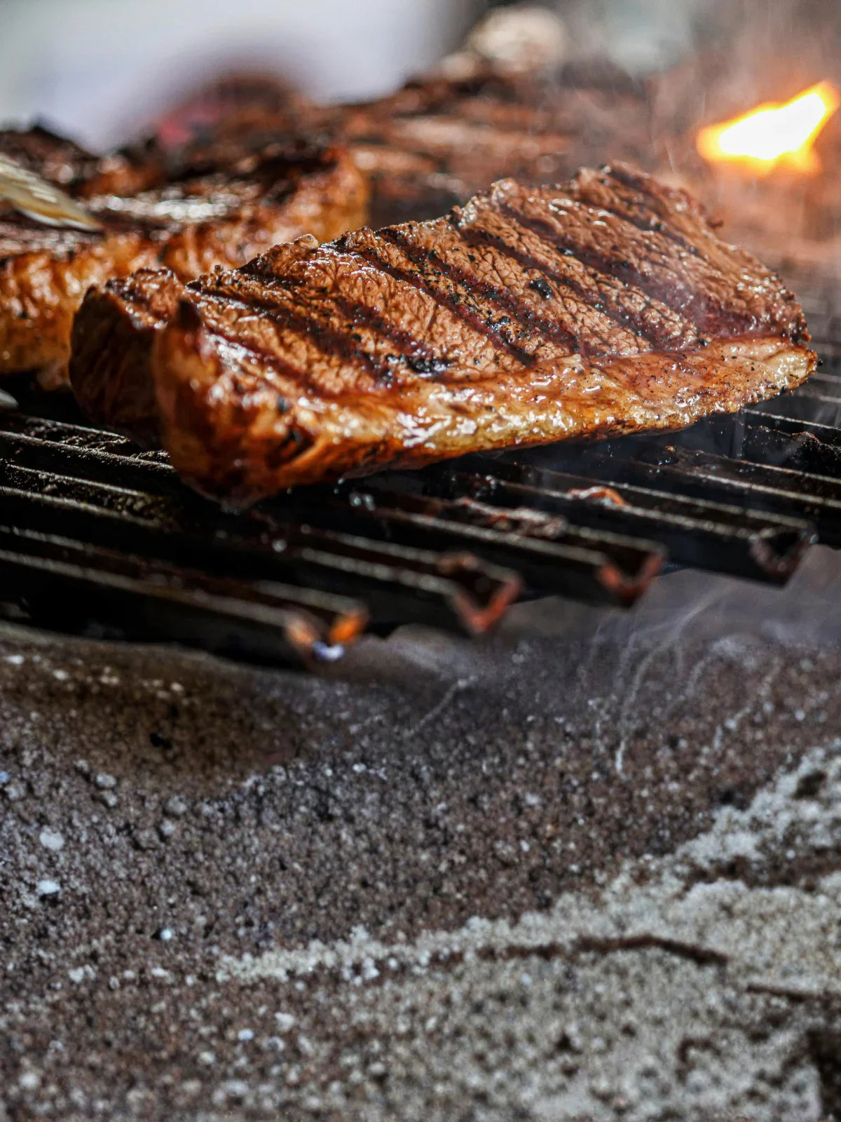 Juicy steak grilling over open flames on a barbecue, showing seared grill marks